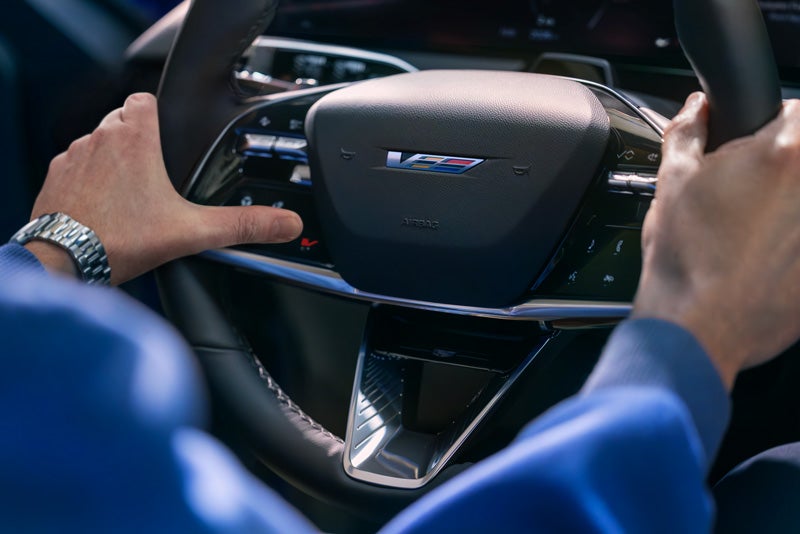 Close-up of a Man About to Press the V-Button on the 2026 OPTIQ-V Steering Wheel | Myrtle Beach Cadillac in Myrtle Beach SC