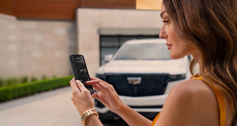 lady checking her mobile with a Cadillac vehicle background | Myrtle Beach Cadillac in Myrtle Beach SC