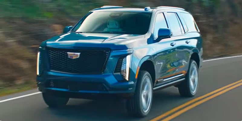 adillac full-size SUV driving outdoors on a sunny day