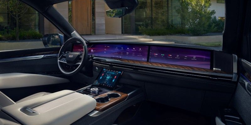 Cadillac interior showcasing a wide infotainment display and wood accents