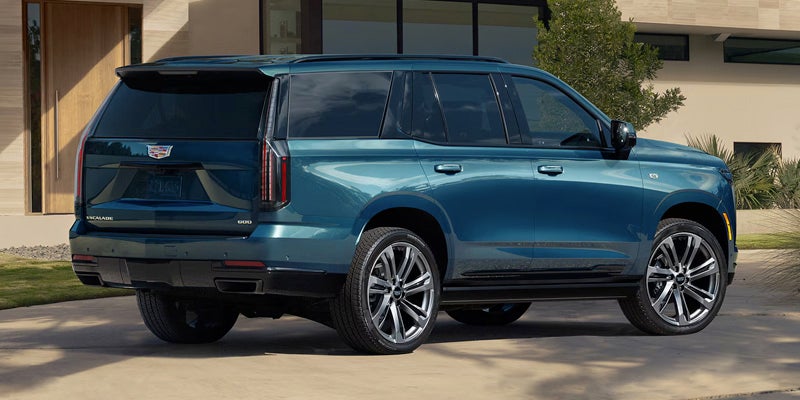 Side and rear view of a blue Cadillac SUV in a residential setting