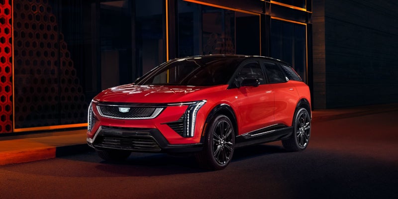 Red Cadillac Lyriq SUV at night in an urban setting.