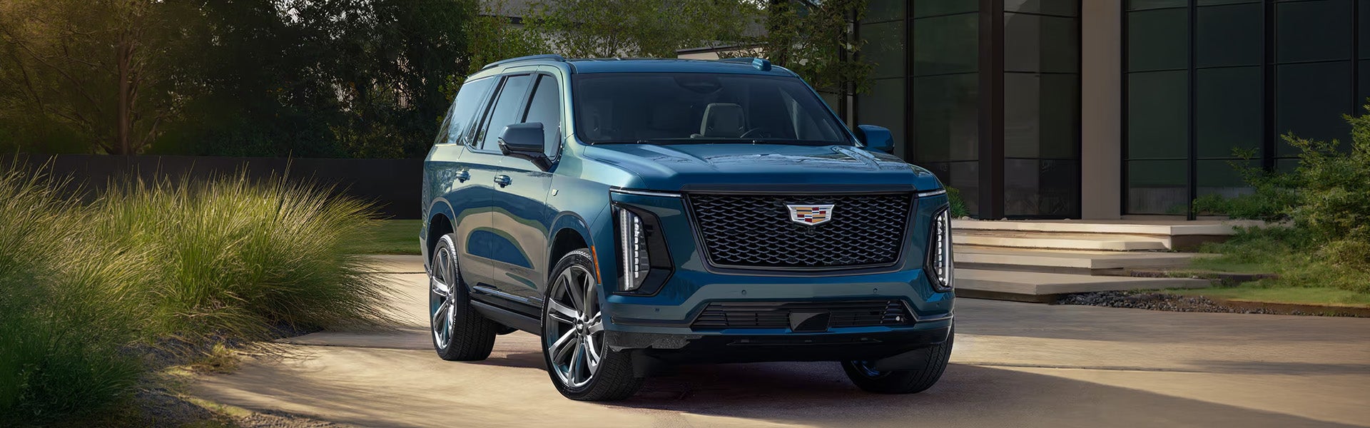 Blue Cadillac SUV parked outside a modern building.